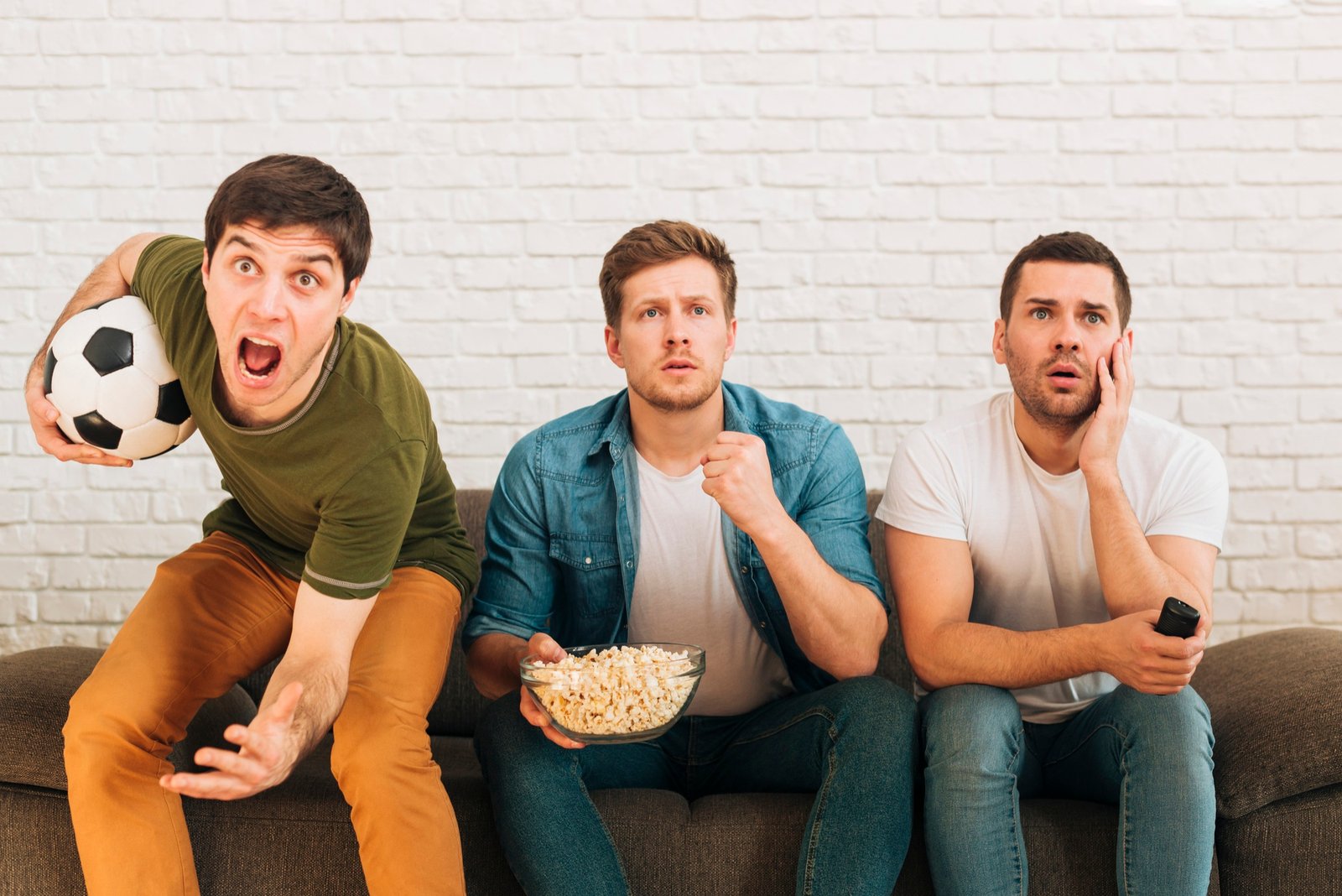 worried male friends sitting sofa watching football match television